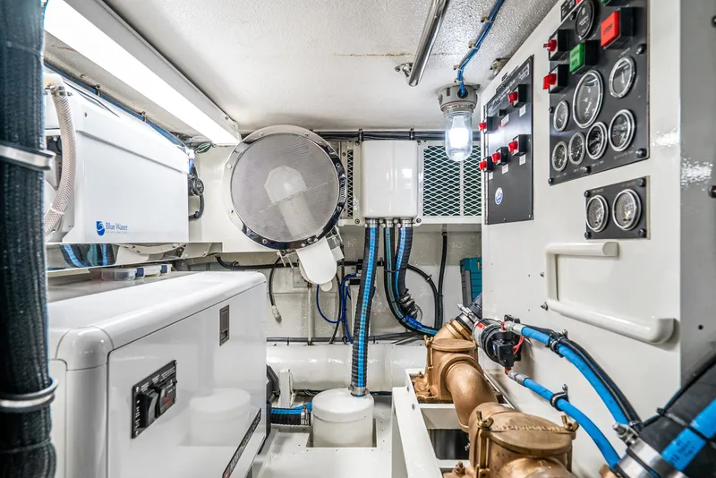 Slide: The Image of Engine room of 1990 Hatteras 58 Sportfish, featuring control panels and mechanical equipment. - 35