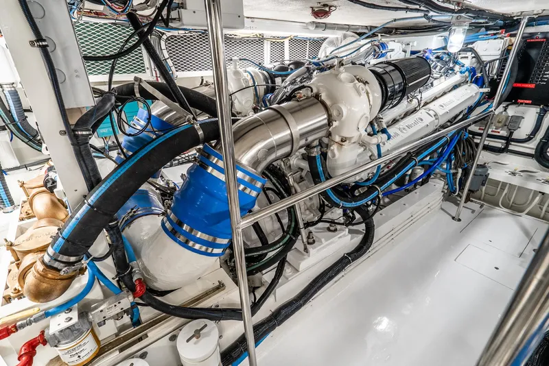 Slide: The Image of Engine room of a 1990 Hatteras 58 Sportfish, showcasing complex machinery and piping. - 43