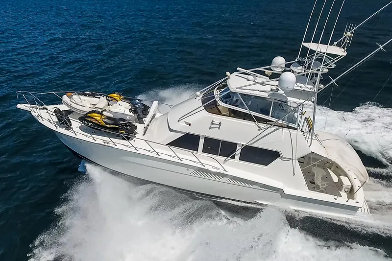 Slide: The Image of 1990 Hatteras 58 Sportfish yacht cruising on open water with jet skis onboard. - 5