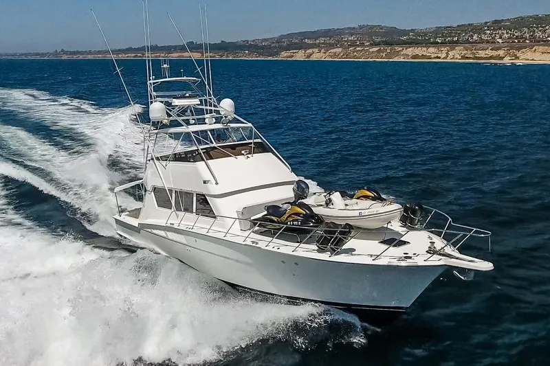 Slide: The Image of 1990 Hatteras 58 Sportfish yacht cruising on open water, showcasing sleek design and powerful performance. - 6