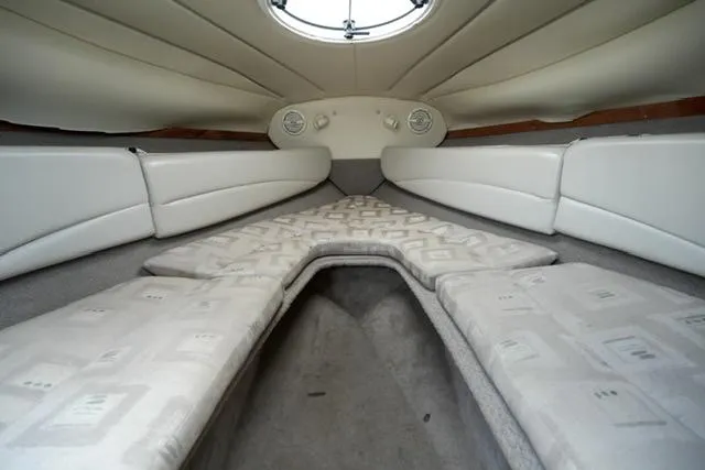 Slide: The Image of Interior cabin of 2002 Four Winns 225 Sundowner boat, featuring cushioned seating and porthole. - 11