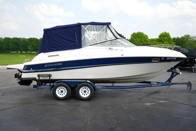 Slide: The Image of 2002 Four Winns 225 Sundowner boat on trailer, blue canopy, parked outdoors. - 3