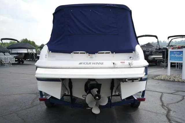 Slide: The Image of 2002 Four Winns 225 Sundowner boat, rear view with blue cover, parked on pavement. - 5