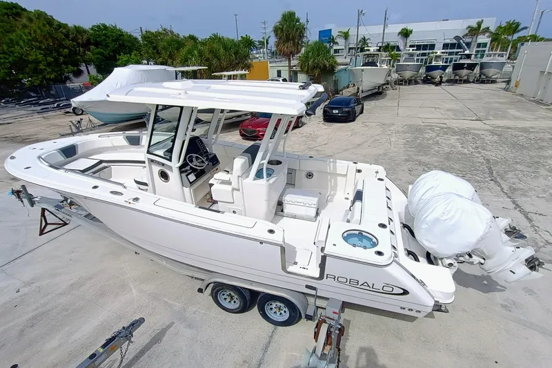 The Image of 2025 Robalo R270 Center Console boat on trailer, parked in a marina lot. - 0
