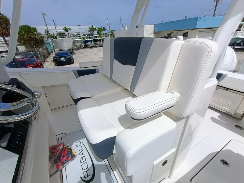Slide: The Image of 2025 Robalo R270 Center Console boat with white and gray seating in a marina setting. - 20