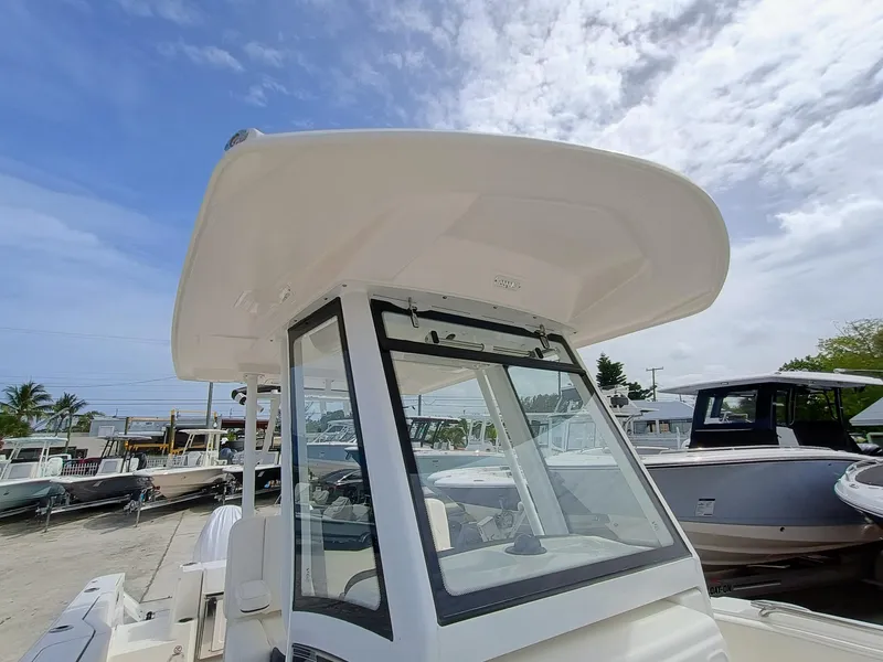 Slide: The Image of 2025 Robalo R270 Center Console boat with T-top, docked under a partly cloudy sky. - 26
