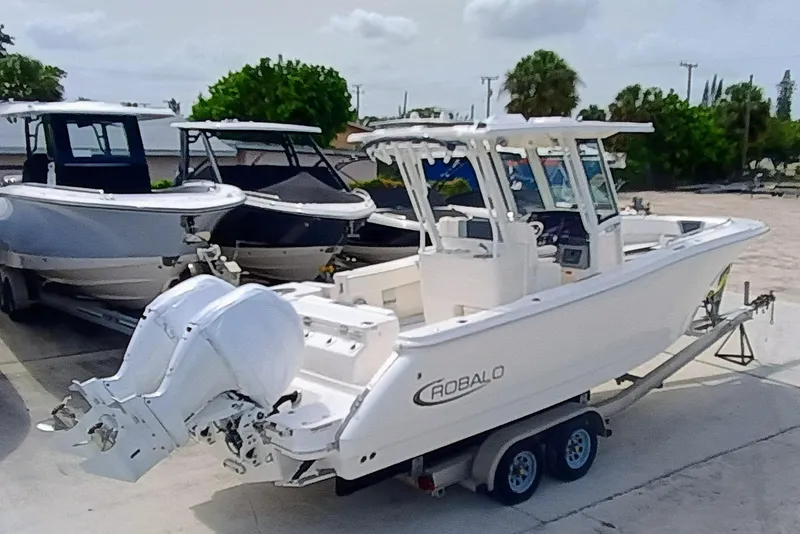 Slide: The Image of 2025 Robalo R270 Center Console boat on trailer, parked outdoors. - 6
