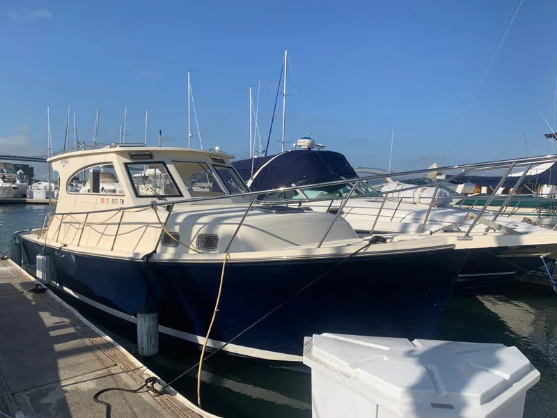 The Image of 2004 Mainship Pilot 30-II Sedan docked at marina under clear blue sky. - 0