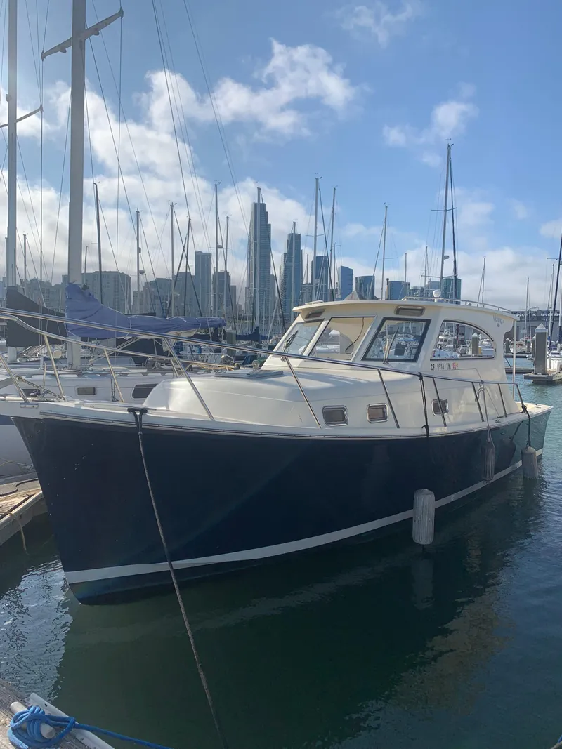 Slide: The Image of 2004 Mainship Pilot 30-II Sedan docked in marina with city skyline background. - 17