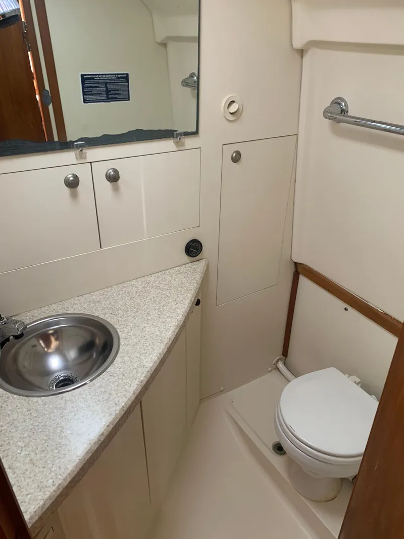 Slide: The Image of 2004 Mainship Pilot 30-II Sedan bathroom with sink, toilet, and storage cabinets. - 8