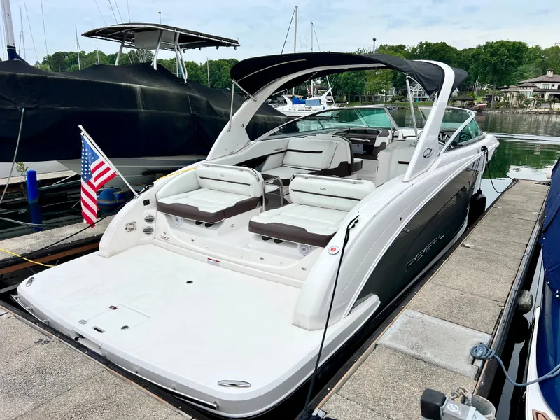 Slide: The Image of 2016 Regal 3200 Bowrider boat docked, featuring spacious seating and American flag. - 3