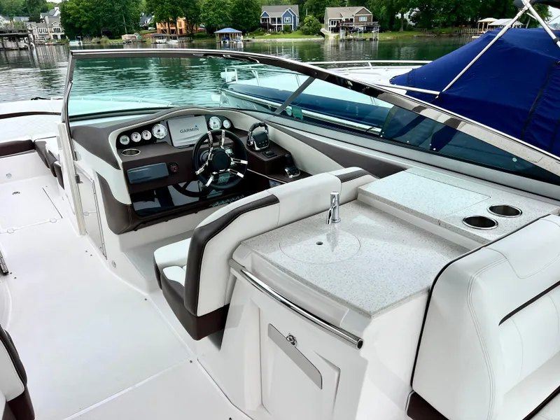 Slide: The Image of 2016 Regal 3200 Bowrider interior with helm, seating, and sink, docked by a lake. - 4