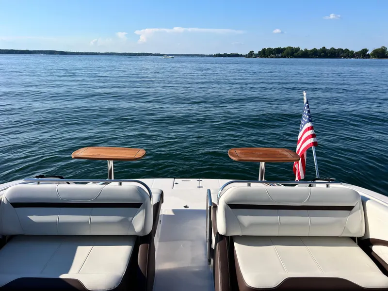 Slide: The Image of 2016 Regal 3200 Bowrider on calm lake with American flag and seating area. - 6