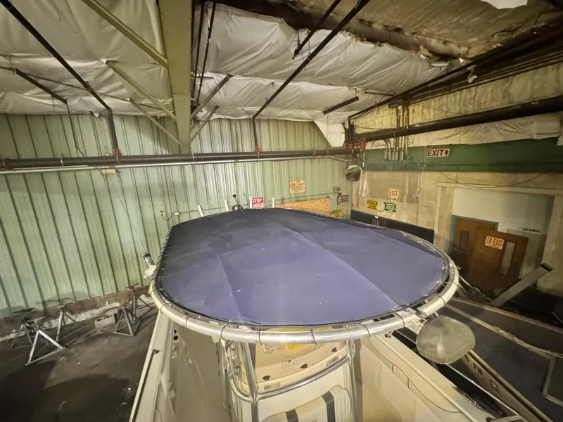 Slide: The Image of 2012 Carolina Skiff Sea Chaser 2400 Offshore boat stored indoors, featuring a blue canopy. - 17