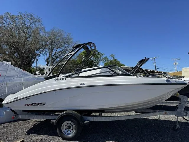 The Image of 2025 Yamaha AR195 boat on trailer, sleek design, parked outdoors under clear blue sky. - 1