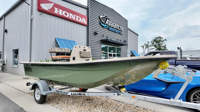 The Image of 2025 Carolina Skiff E18 JVX Swamp Edition boat on trailer outside dealership. - 1