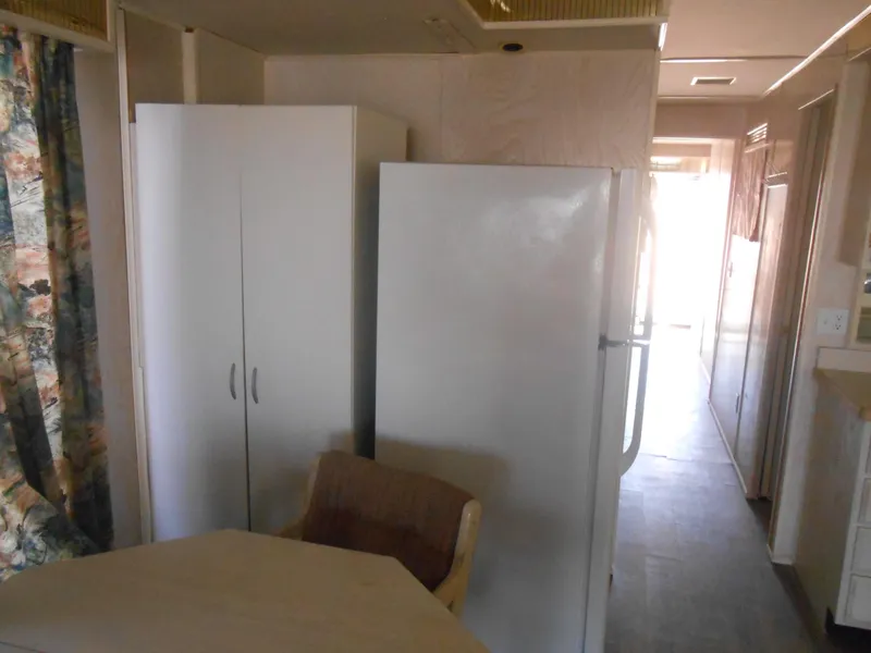 Slide: The Image of Interior of a 1994 Stardust Cruisers houseboat with fridge, cabinet, and chair. - 10