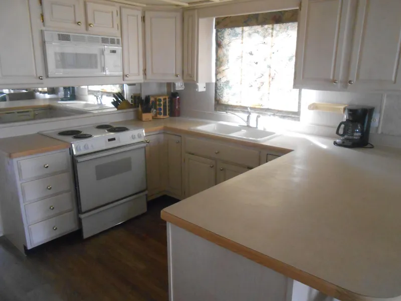 Slide: The Image of Kitchen interior of a 1994 Stardust Cruisers houseboat with white cabinets and appliances. - 11