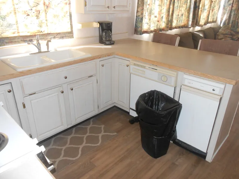 Slide: The Image of 1994 Stardust Cruisers houseboat kitchen with white cabinets, dishwasher, and countertop. - 12