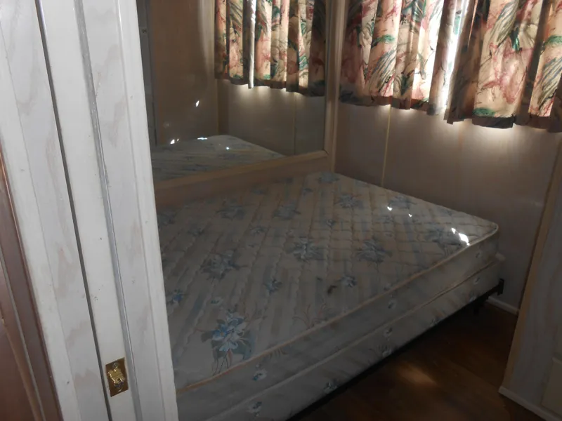 Slide: The Image of 1994 Stardust Cruisers houseboat bedroom with floral curtains and mattress. - 13