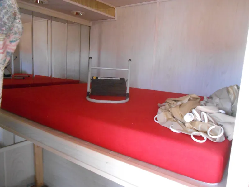 Slide: The Image of 1994 Stardust Cruisers houseboat interior with red mattress and folded curtains. - 18