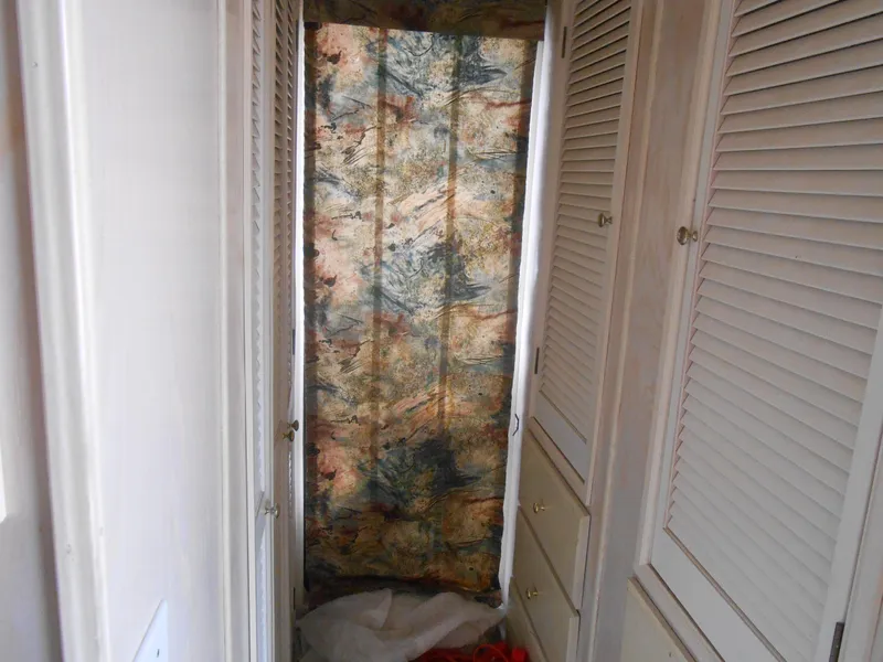 Slide: The Image of Narrow hallway in a 1994 Stardust Cruisers houseboat with patterned curtain and white cabinets. - 20