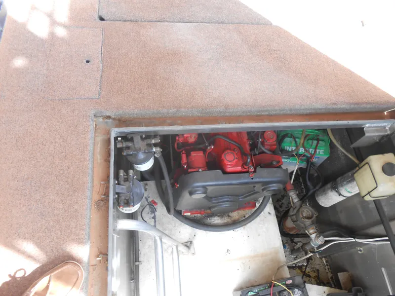 Slide: The Image of Engine compartment of a 1994 Stardust Cruisers houseboat, featuring a red engine and battery. - 26