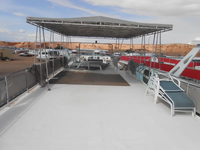 Slide: The Image of 1994 Stardust Cruisers houseboat deck with canopy and lounge chairs, docked in a marina. - 32