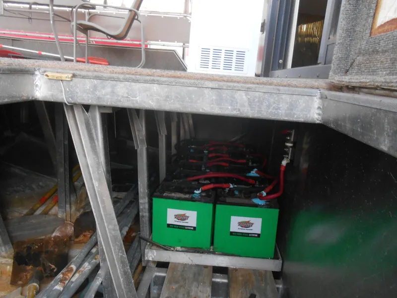 Slide: The Image of 1994 Stardust Cruisers houseboat battery compartment with green batteries and red cables. - 36