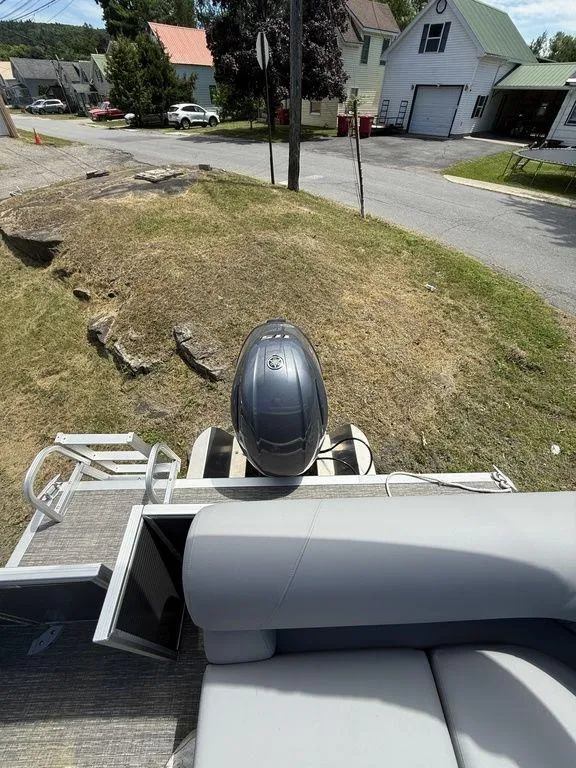 Slide: The Image of 2025 Bennington S L-Bench 18SVL pontoon boat with outboard motor, parked on grass. - 13