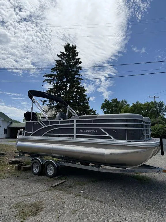 Slide: The Image of 2025 Bennington S L-Bench 18SVL pontoon boat on trailer under a partly cloudy sky. - 3