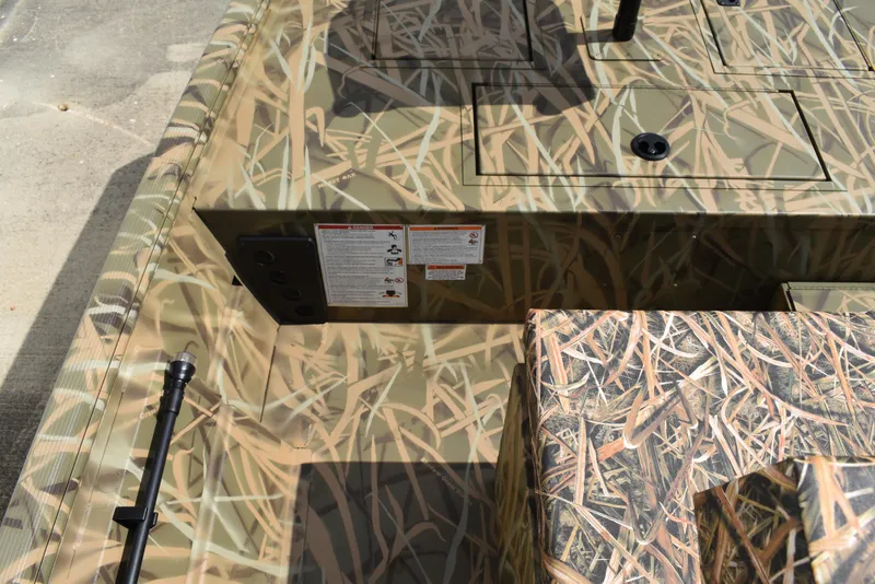 Slide: The Image of 2025 Lowe RX1860 Tunnel Jet boat interior with camouflage design and storage compartments. - 16