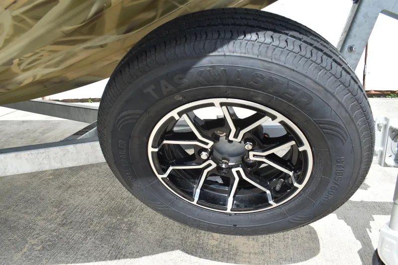 Slide: The Image of Trailer wheel of 2025 Lowe RX1860 Tunnel Jet, featuring Taskmaster tire and stylish black alloy rim. - 25