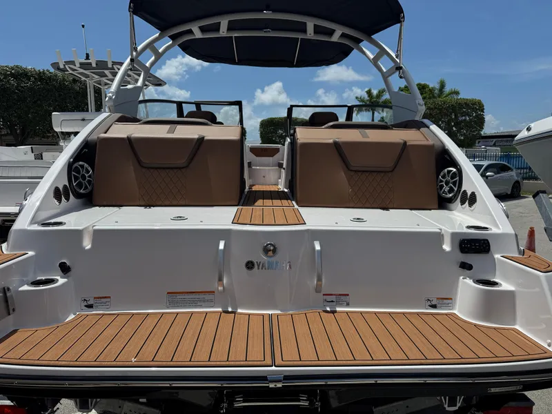 Slide: The Image of 2025 Yamaha Boats 222S with teak deck and luxurious seating, docked under clear skies. - 23