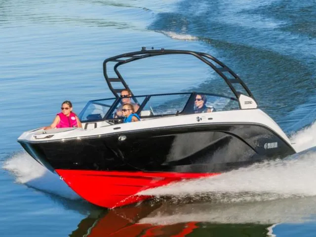 Slide: The Image of 2025 Yamaha Boats 222SD cruising on water with passengers, featuring sleek black and red design. - 34