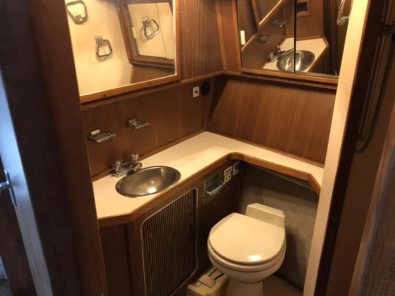 Slide: The Image of 1987 Sea Ray 360 Aft Cabin bathroom with wood paneling, sink, and toilet. - 10