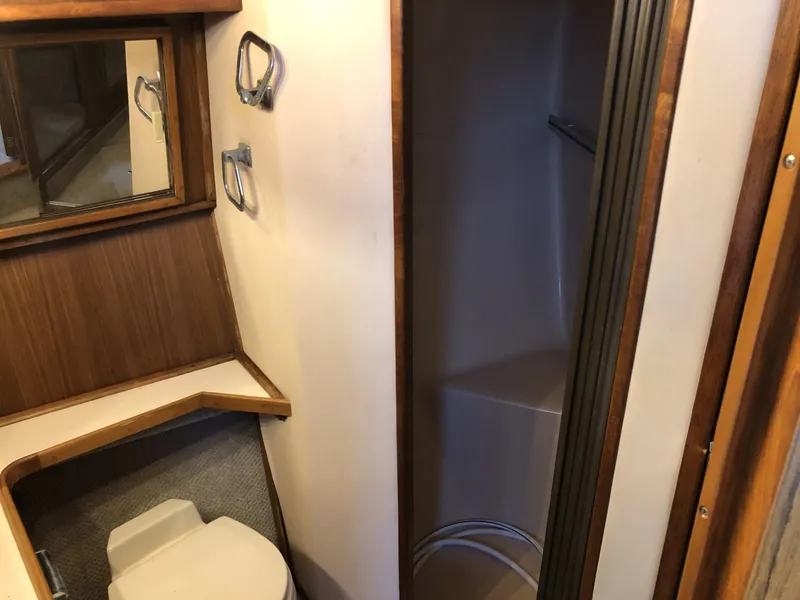 Slide: The Image of 1987 Sea Ray 360 Aft Cabin bathroom with toilet, shower, and wooden accents. - 11