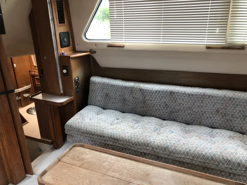 Slide: The Image of 1987 Sea Ray 360 Aft Cabin interior with sofa, wooden table, and window blinds. - 6