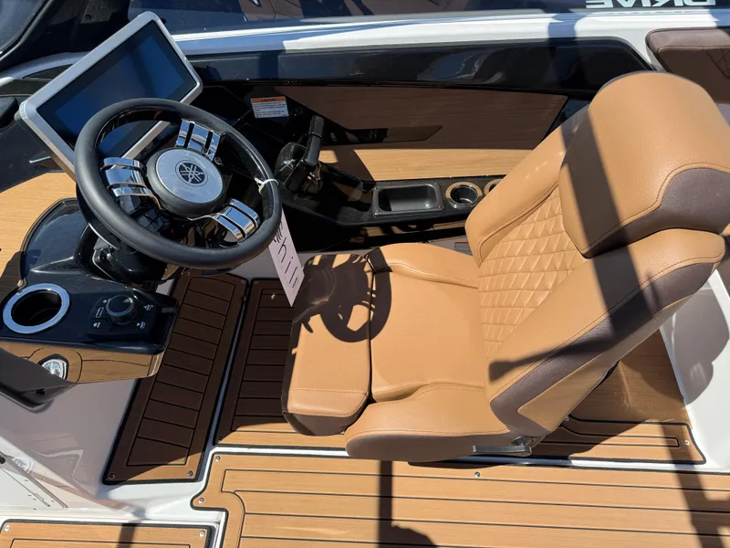 Slide: The Image of 2025 Yamaha Boats 222SD cockpit with tan seating and modern steering wheel. - 10