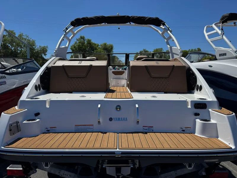 Slide: The Image of 2025 Yamaha Boats 222SD, rear view, showcasing spacious deck and seating, under clear blue sky. - 2