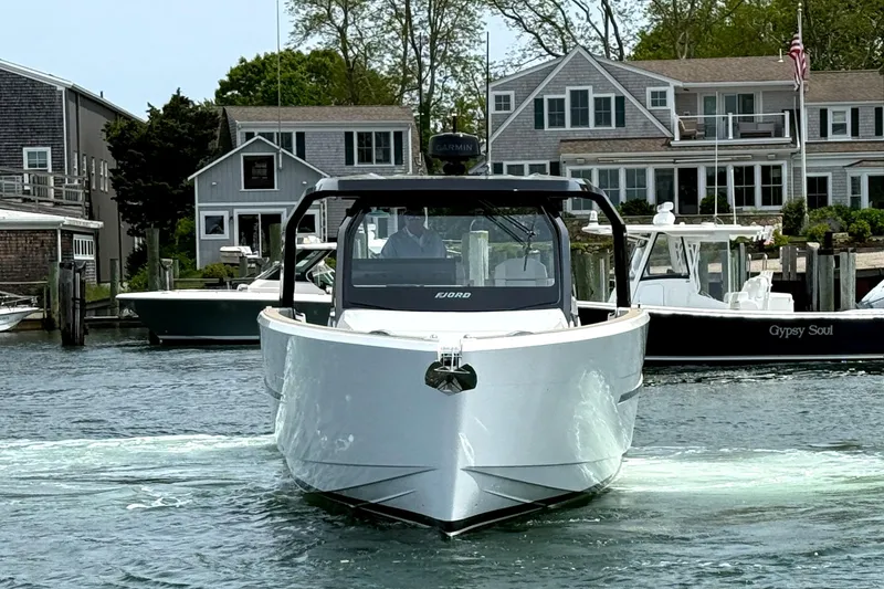 Slide: The Image of 2025 Fjord 39 XP boat cruising in a marina with waterfront homes in the background. - 2