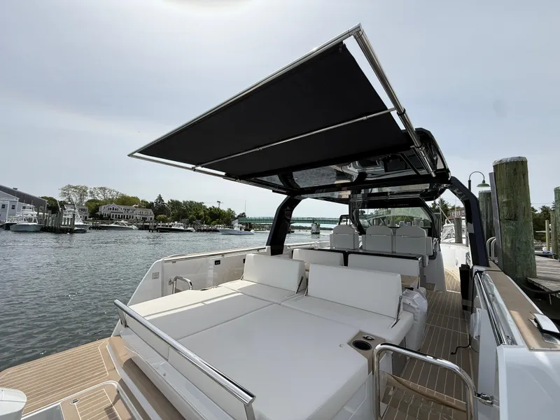 Slide: The Image of 2025 Fjord 39 XP yacht with sunshade, docked by a scenic waterfront. - 23