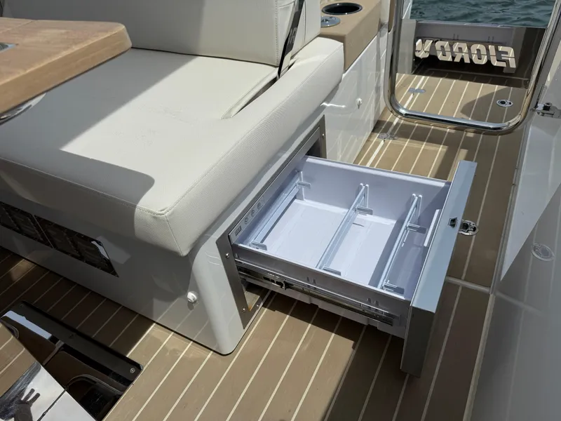 Slide: The Image of Open storage drawer on 2025 Fjord 39 XP boat, featuring beige seating and wood-patterned flooring. - 32