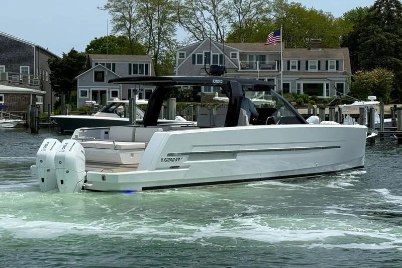 Slide: The Image of 2025 Fjord 39 XP boat docked near waterfront homes, featuring sleek design and dual engines. - 9