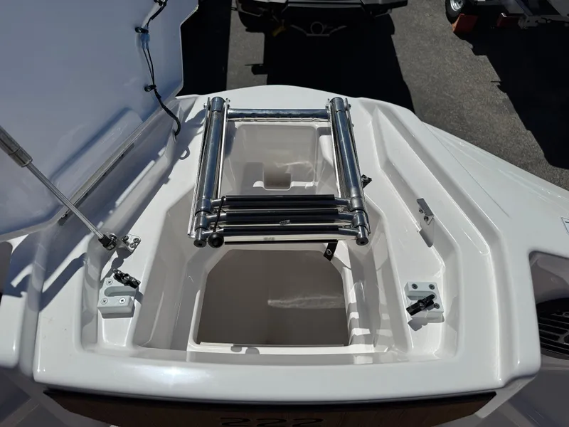 Slide: The Image of 2025 Yamaha Boats 222SD bow storage compartment with ladder, open lid, and sleek design. - 23