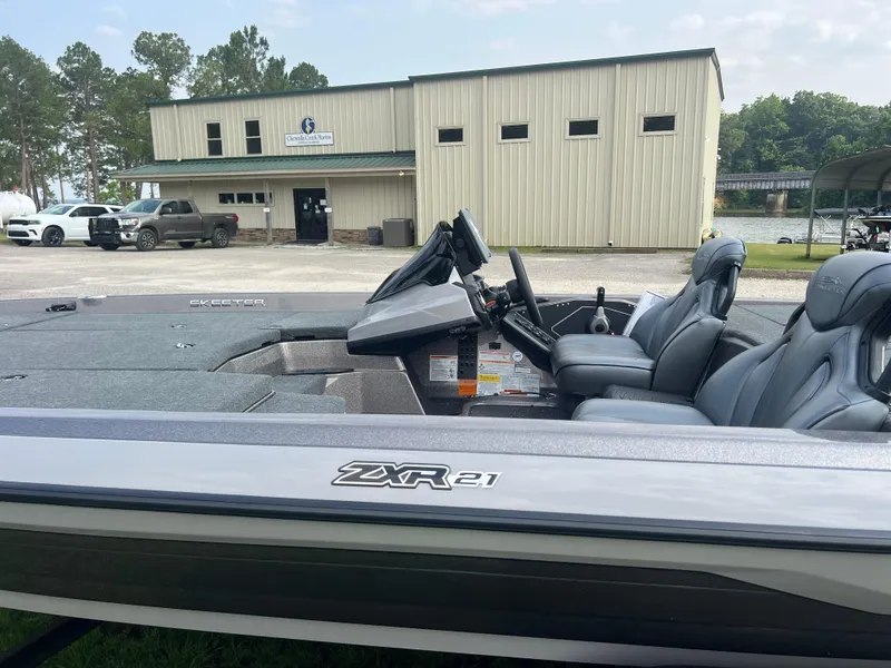 Slide: The Image of 2025 Skeeter ZXR 21 boat parked near a building with trees in the background. - 2