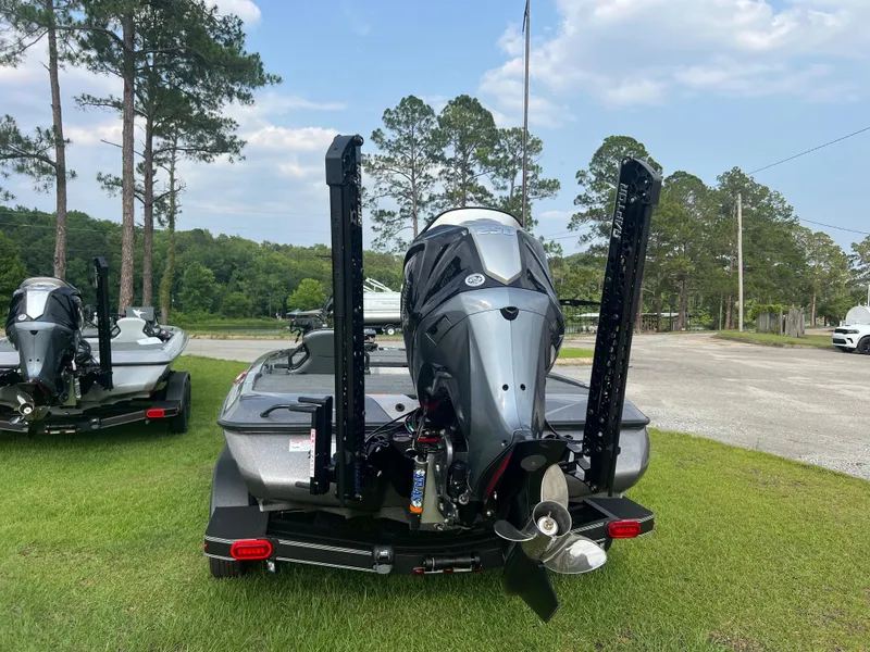 Slide: The Image of 2025 Skeeter ZXR 21 boat on grass, rear view with motor and trees in background. - 6