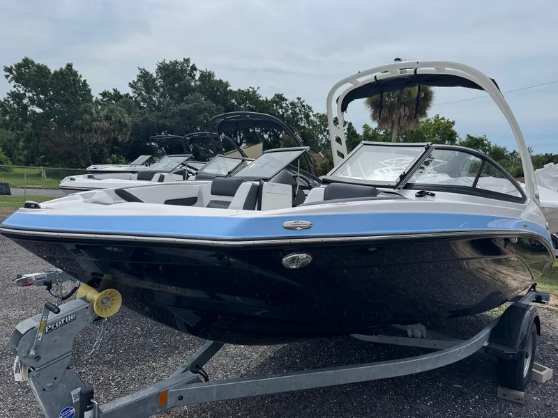 Slide: The Image of 2025 Yamaha Boats 195S on trailer, sleek design, blue and black exterior, parked outdoors. - 1