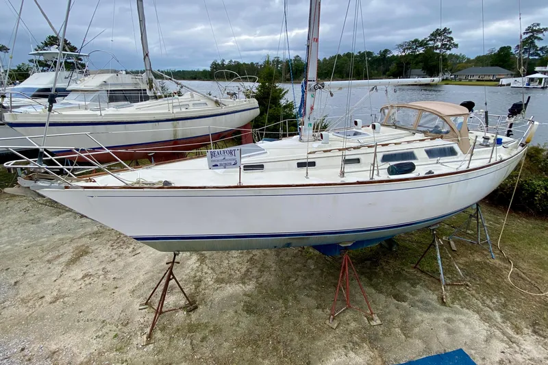 The Image of 1986 Sabre 36 sailboat on stands near a waterfront, overcast sky. - 0