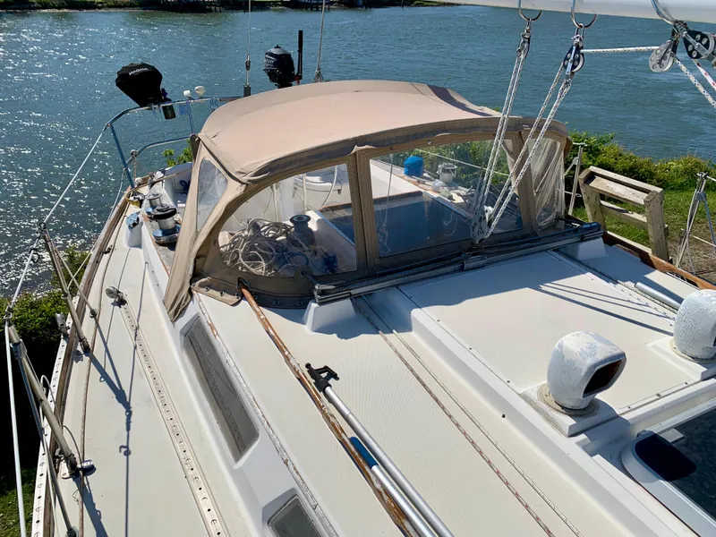Slide: The Image of 1986 Sabre 36 sailboat with beige canopy, docked by a scenic waterfront. - 12